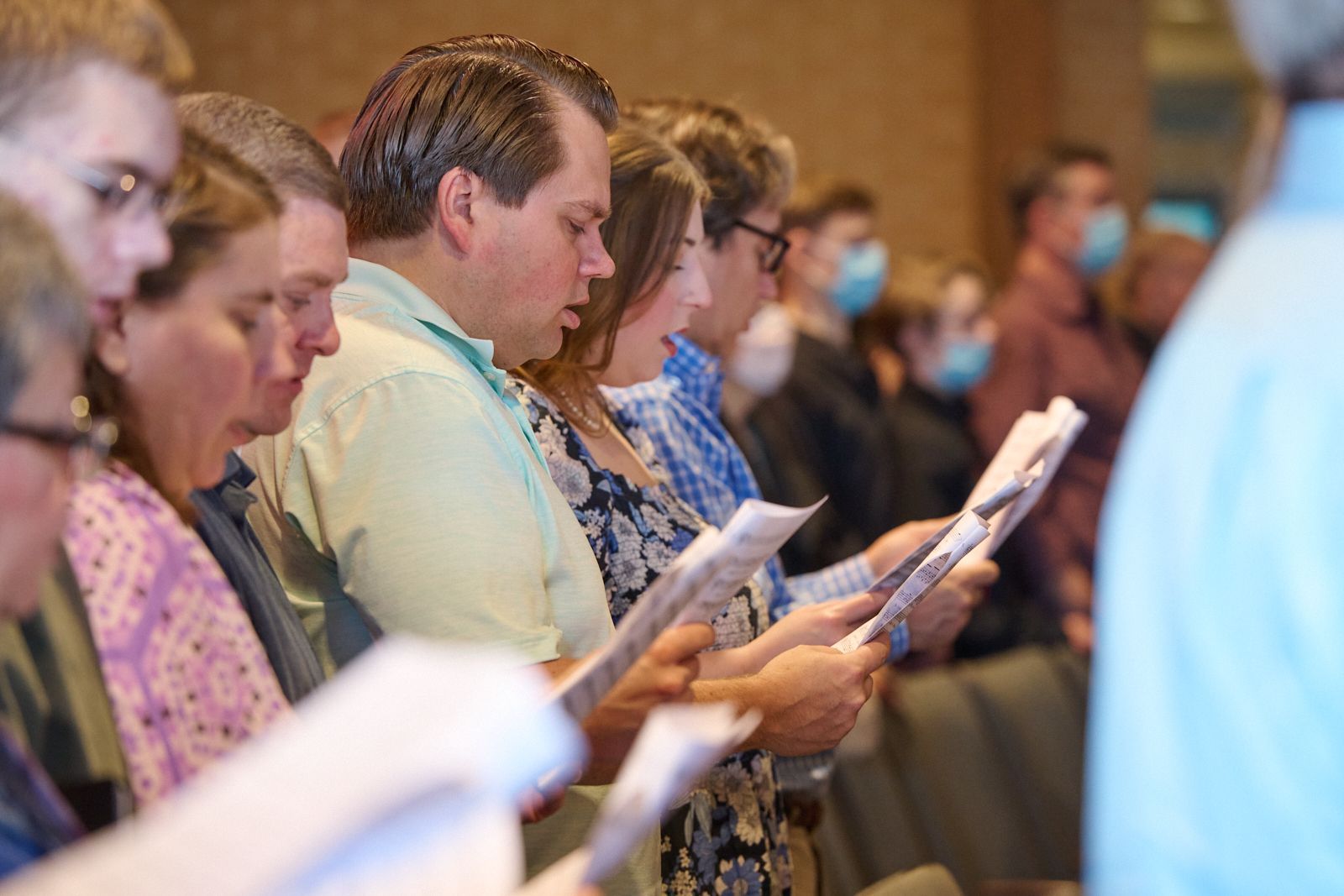 a group of people are sitting in a bible based church with their hands on their chests 