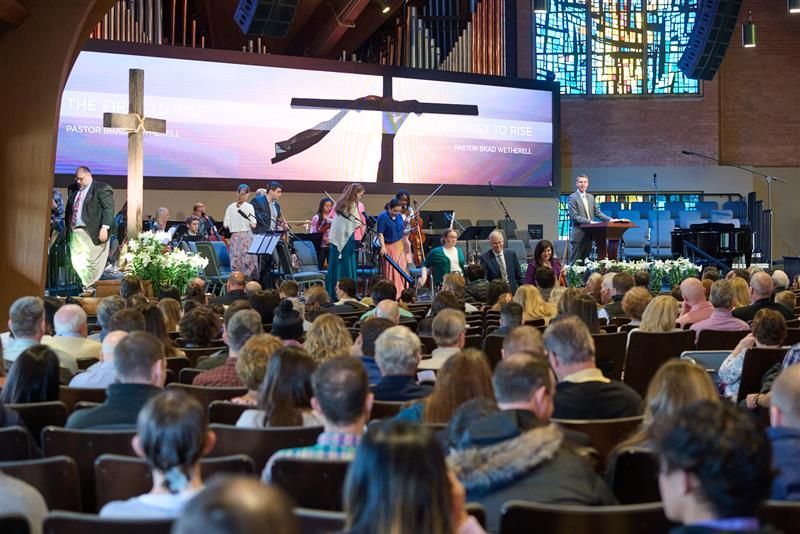 A large group of people are sitting in a church watching a service.