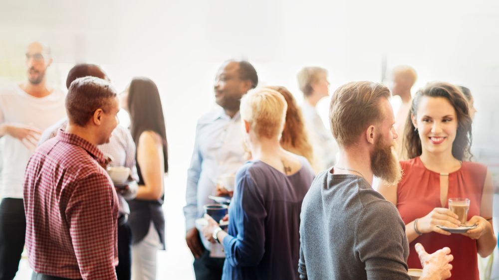 A group of church goers are standing in a room talking to each other.