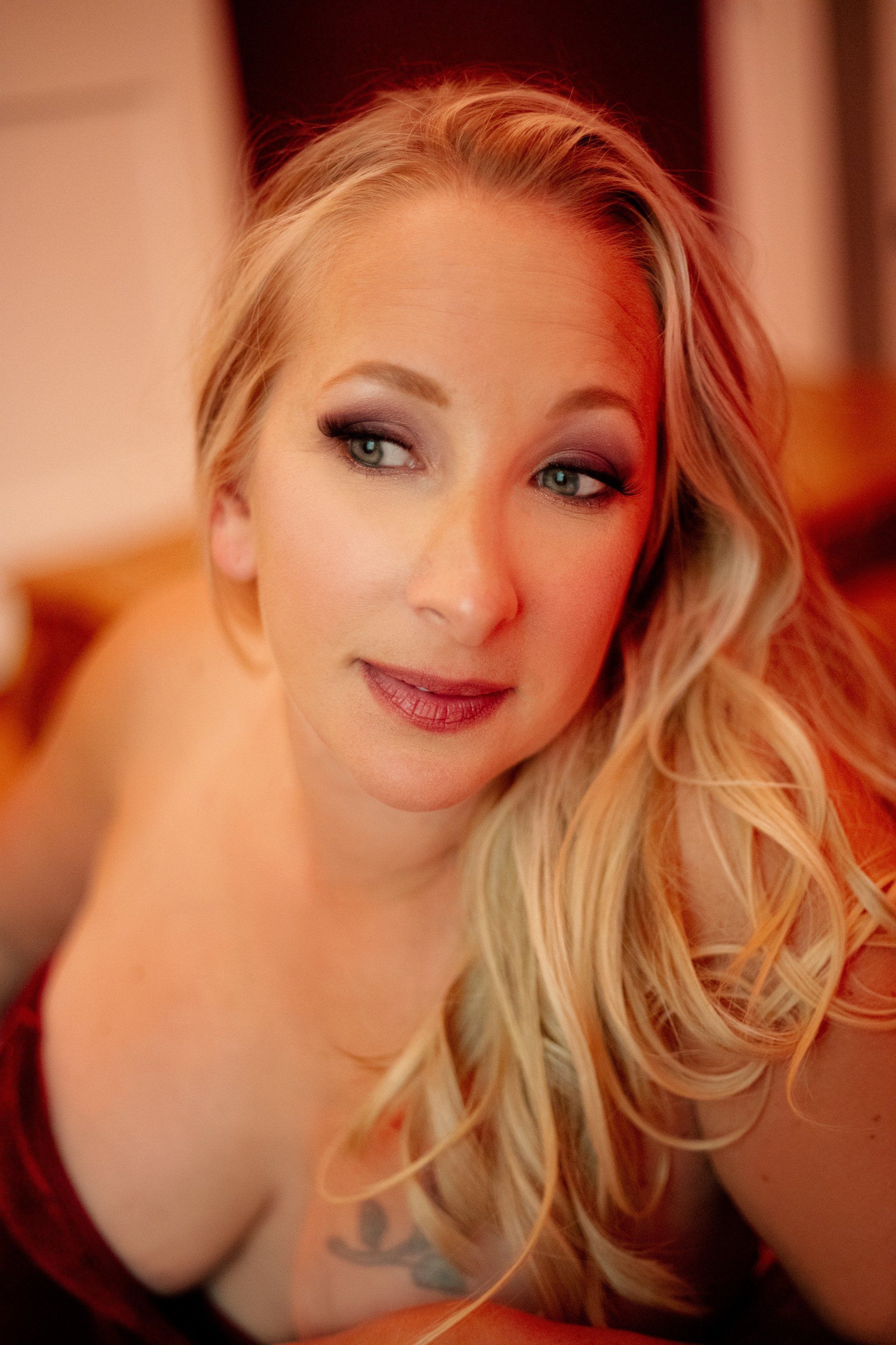 Portrait of a blonde woman with smoky eye makeup, looking off-camera in warm indoor light