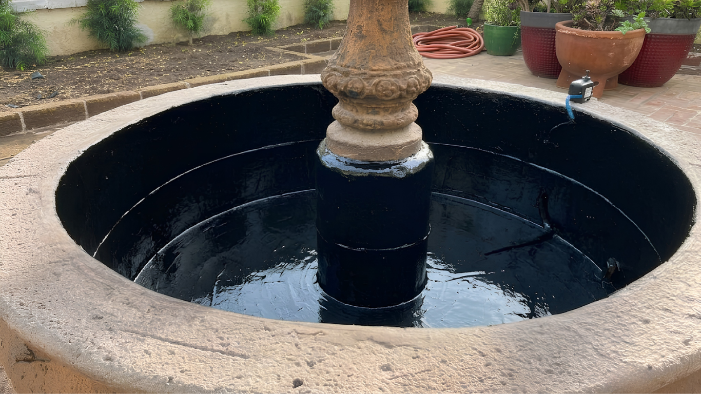 Circular stone fountain with dark water and a central carved pillar in an outdoor courtyard