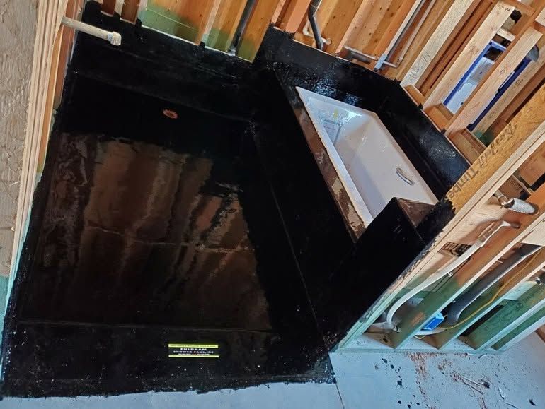 Black rectangular bathtub under construction with wood framing and a white tub insert.