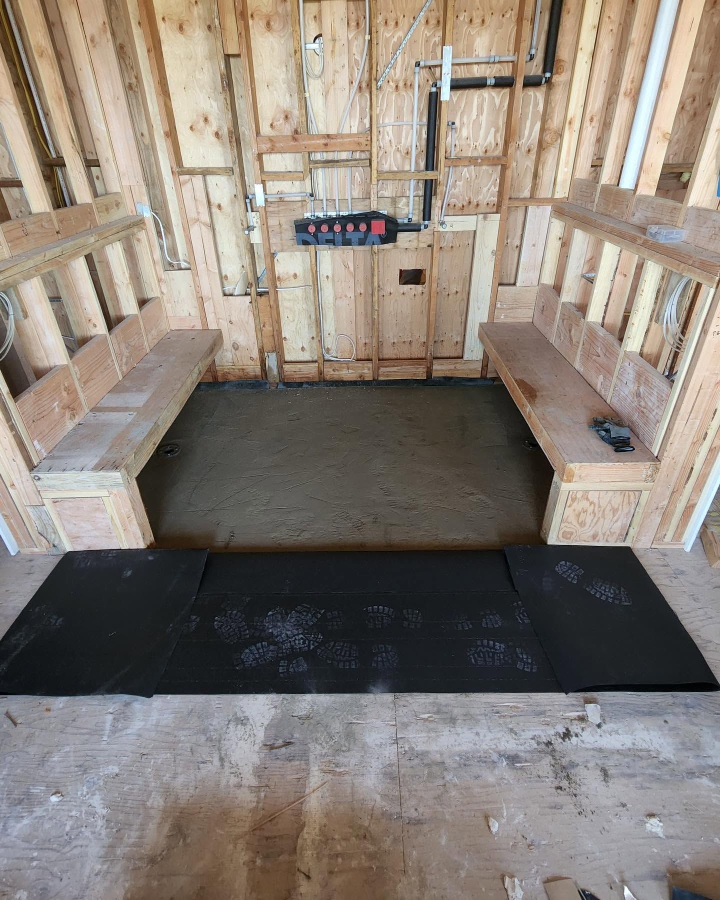 Unfinished shed interior with two wooden benches and a newly poured concrete floor.
