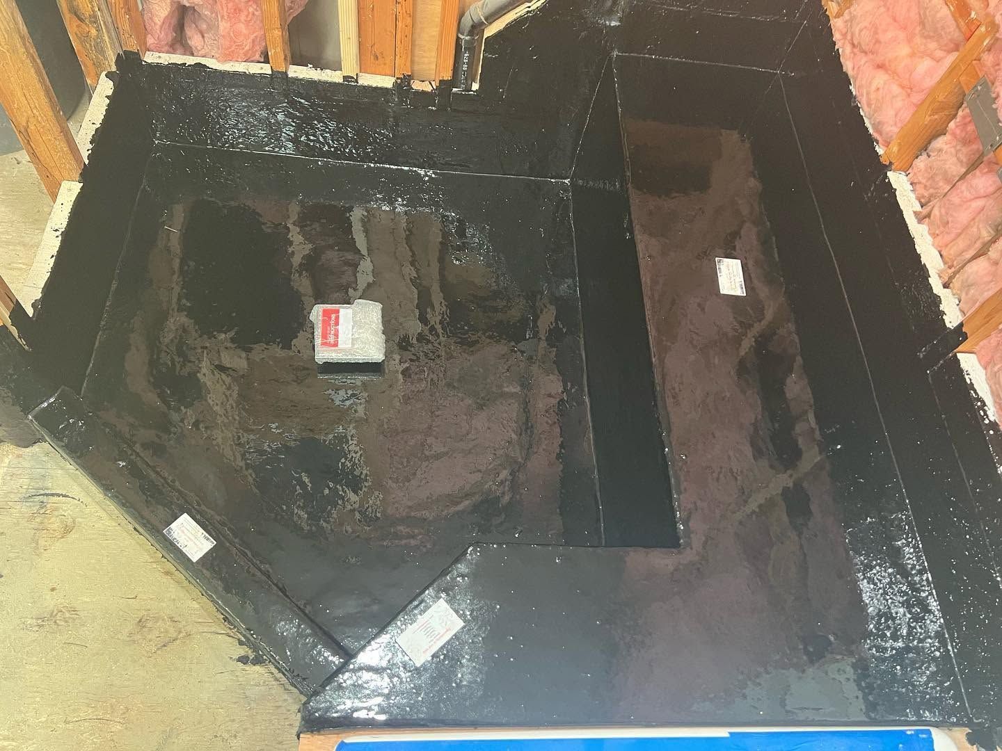 Black-lined rectangular container or pit inside a brick-walled space, with a central divider and labels on the bottom.