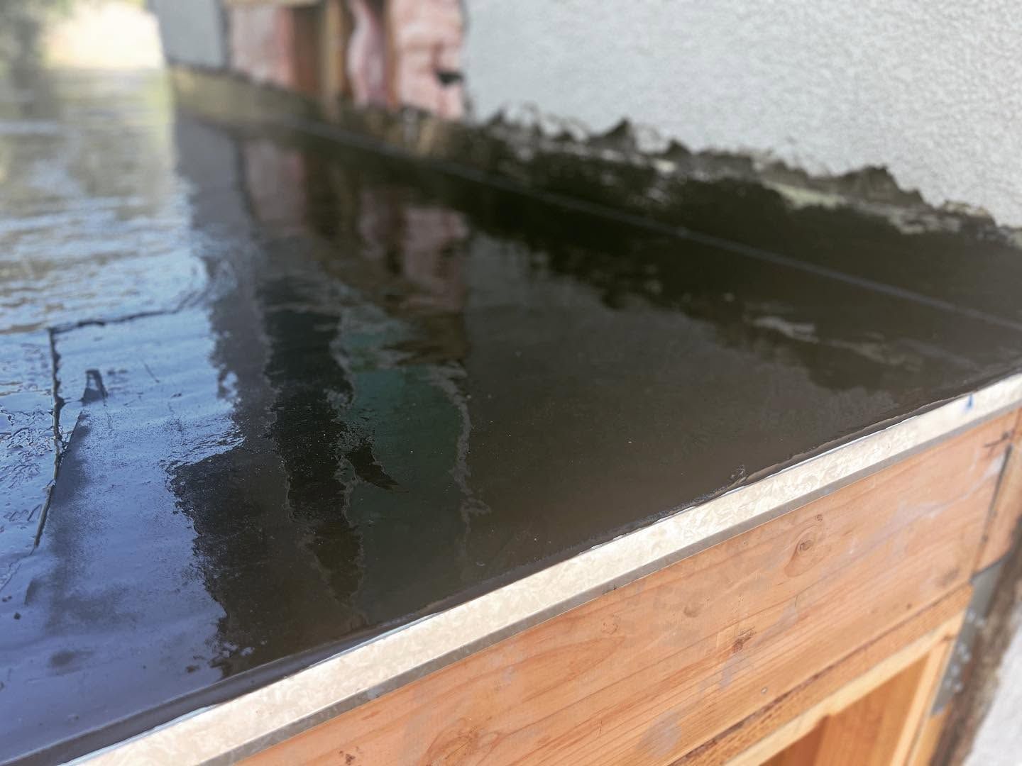 Wet concrete being smoothed in a wooden form outdoors