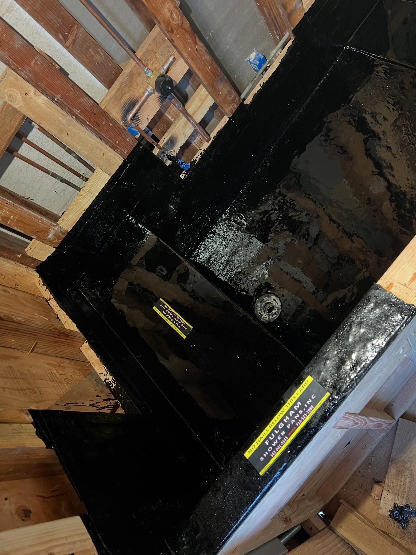 Black appliance on a wood floor beside a brick wall, with yellow labels and a reflective glass front.