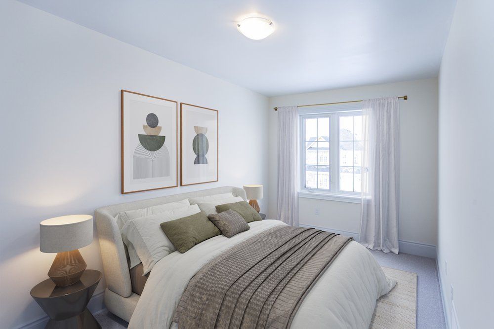 A bedroom with a bed , two lamps , and two paintings on the wall.