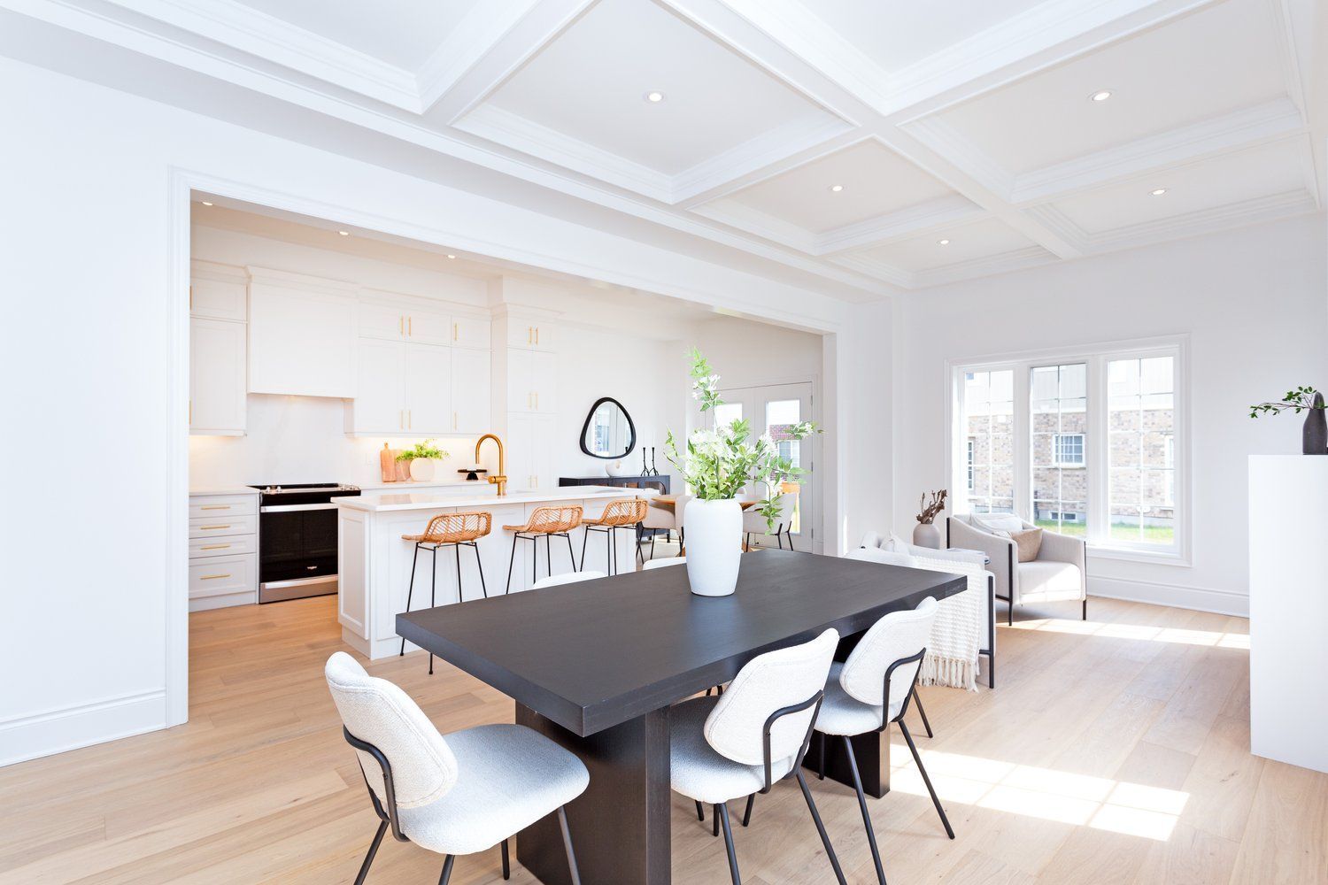 A dining room with a table and chairs and a kitchen in the background.