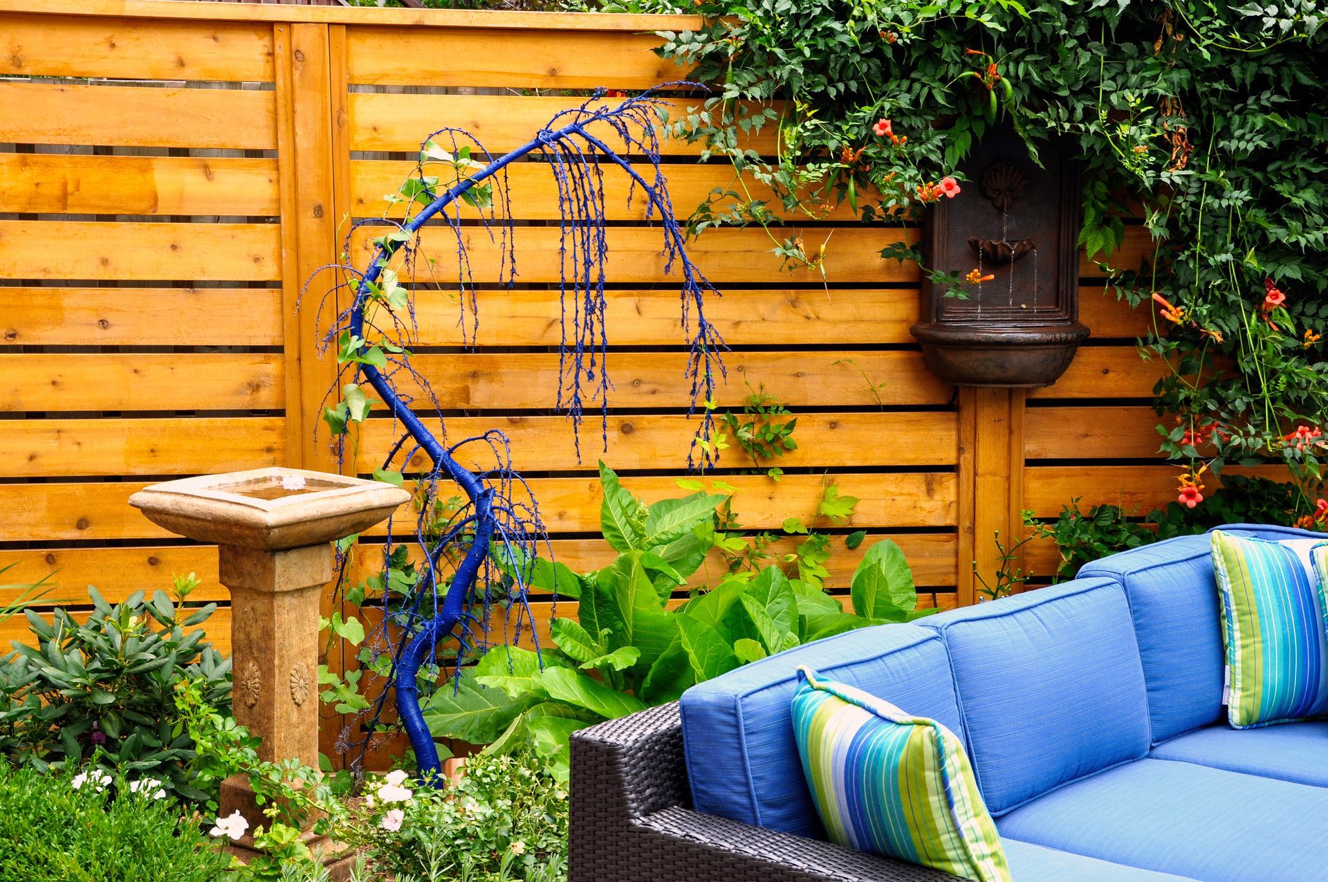 A blue couch is sitting in front of a wooden fence.