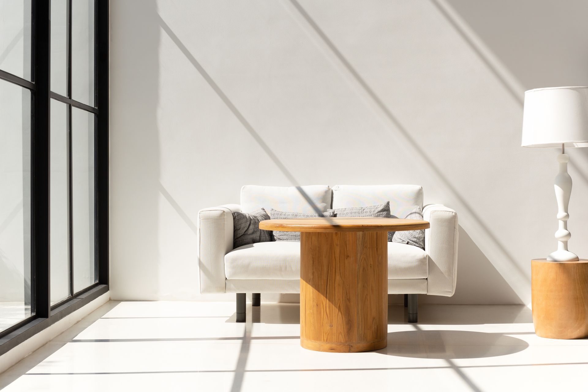 A living room with a couch , table , lamp and window.