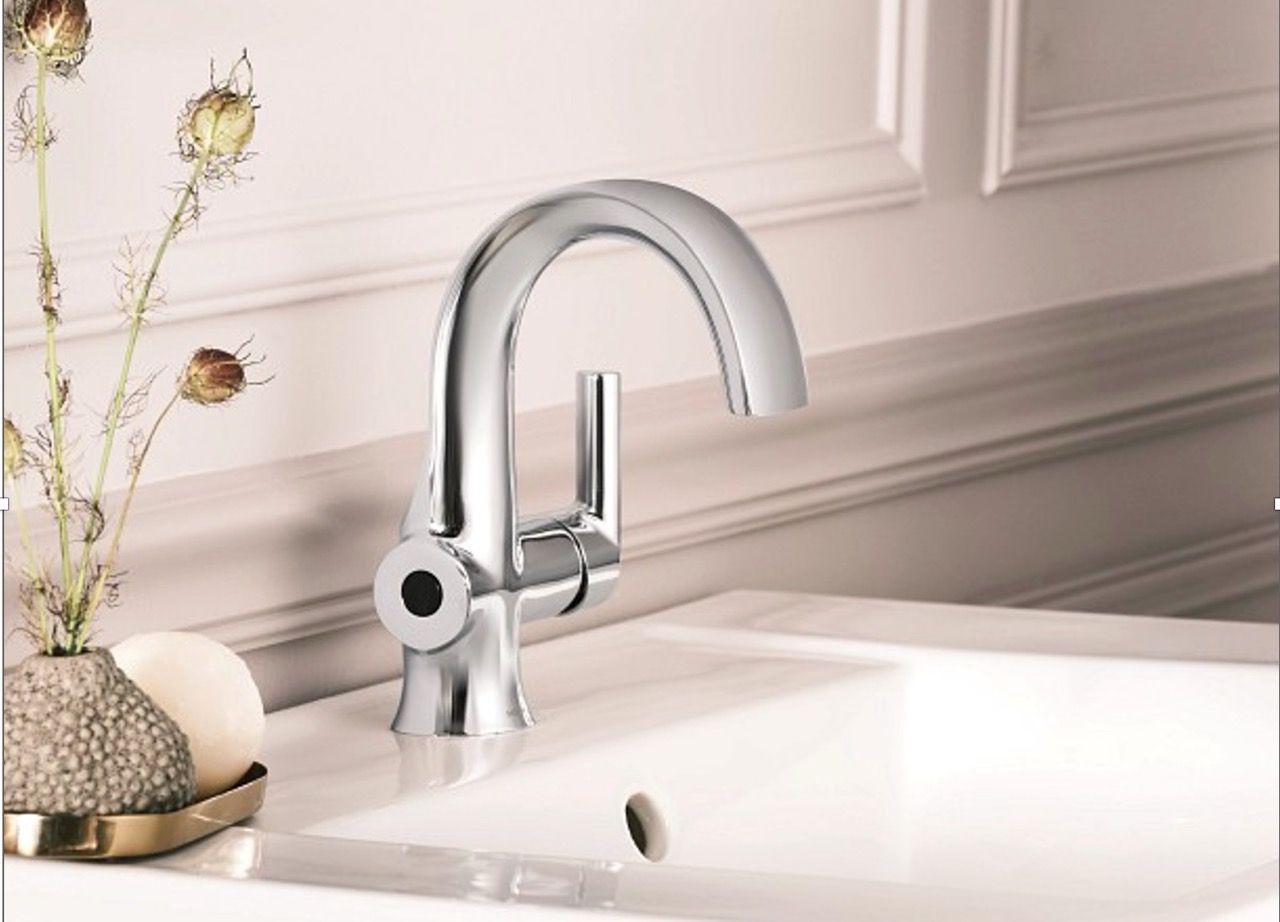 Chrome faucet over a white sink, with a small decorative vase on the counter.