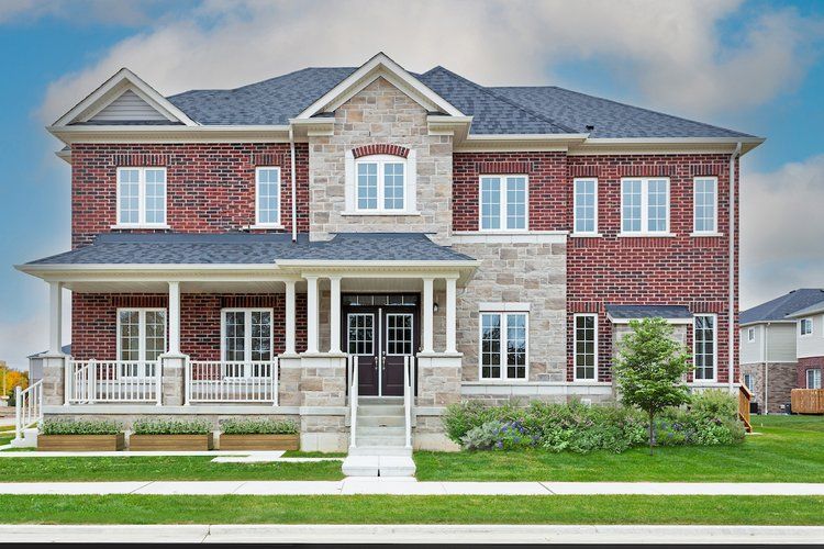 A large brick and stone house with a blue roof and white windows.