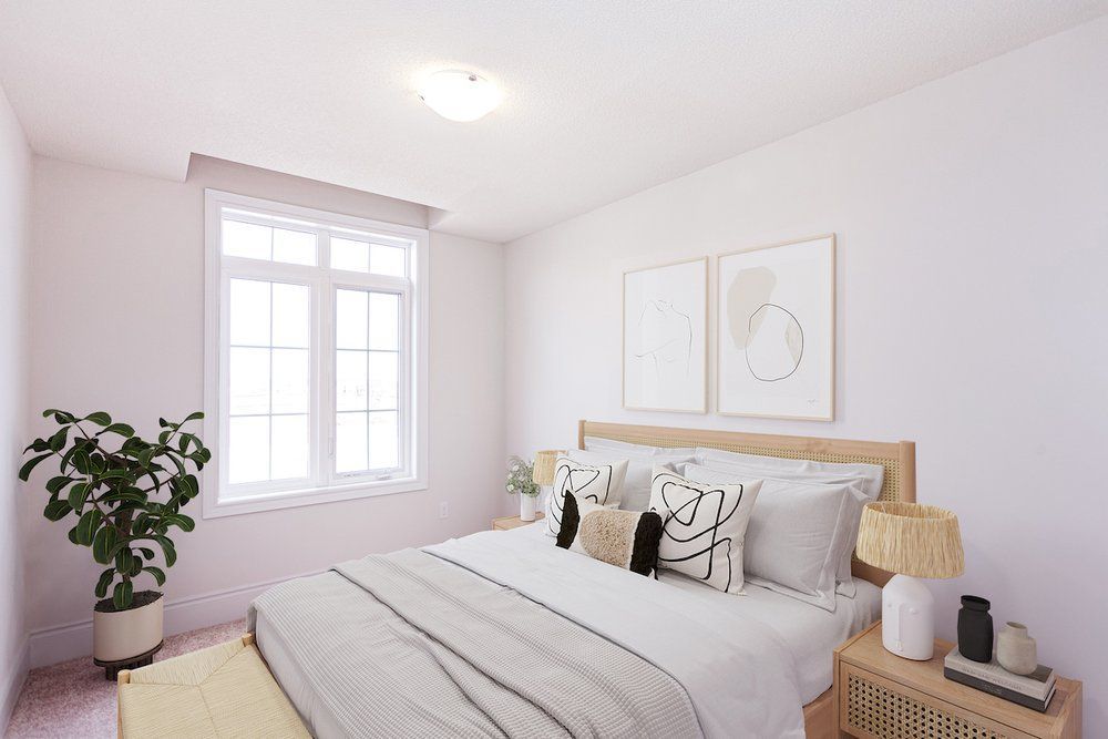 A bedroom with a large bed , two windows and a plant.