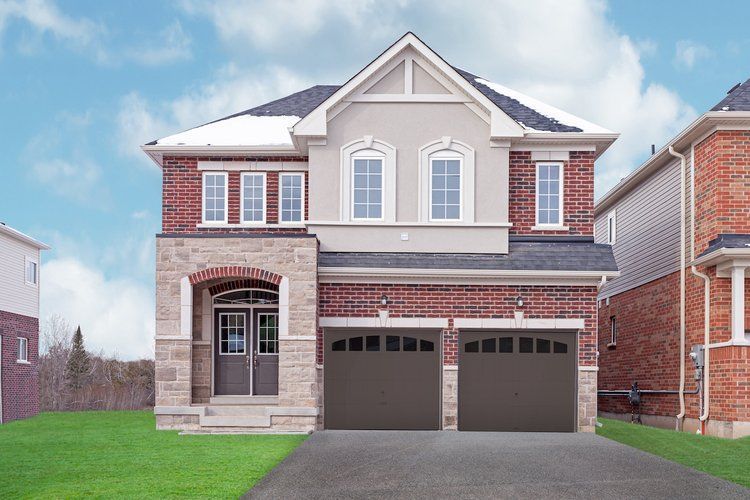 A large brick house with two garage doors and a driveway