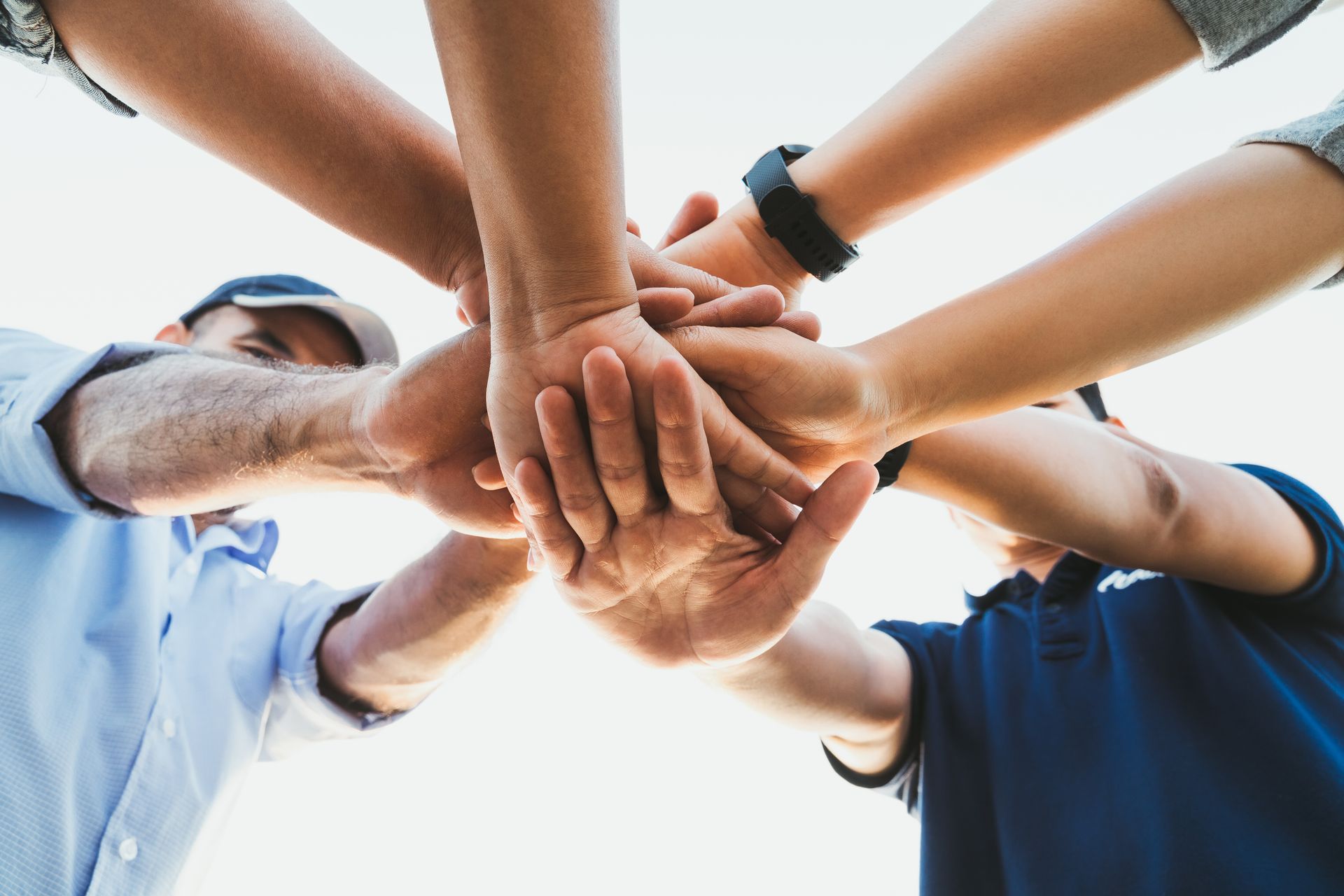 Hands of several people stacked in a team huddle, showing unity.