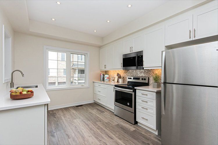 A kitchen with stainless steel appliances and white cabinets.