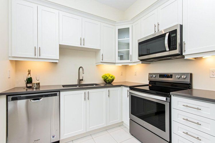 A kitchen with stainless steel appliances and white cabinets.