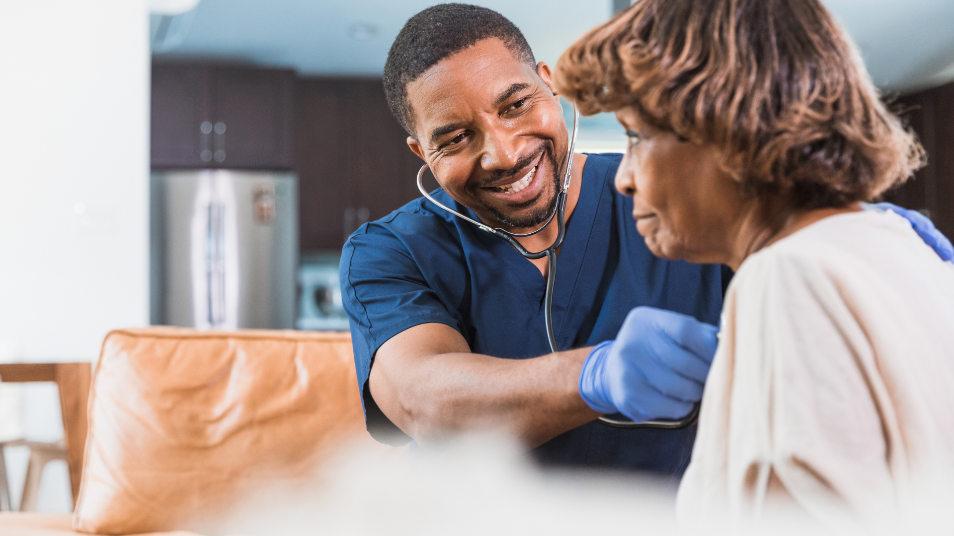 Medical professional using a stethoscope on a patient in a home setting.