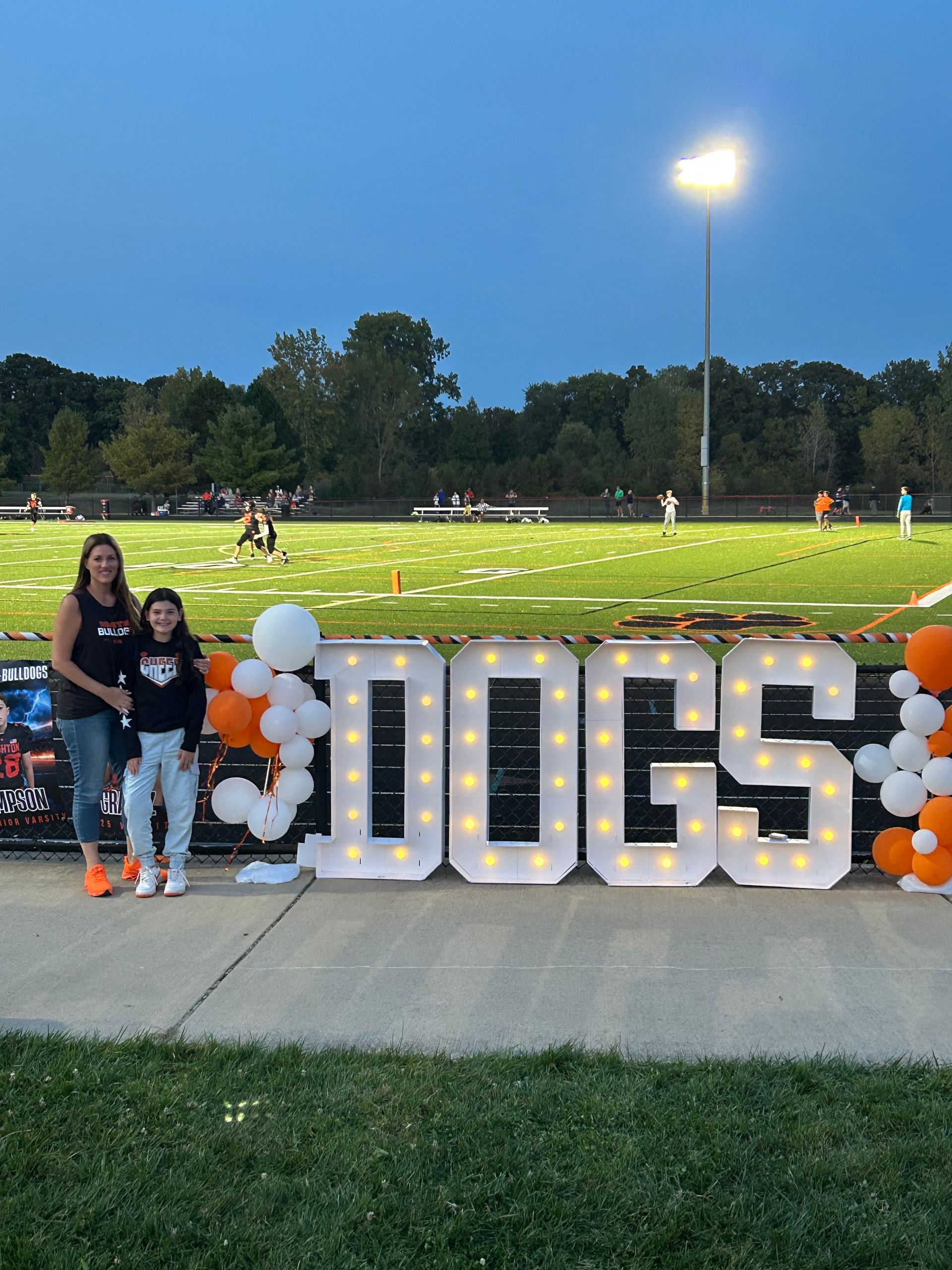 Four people in black and orange baseball outfits posing together at a sports event