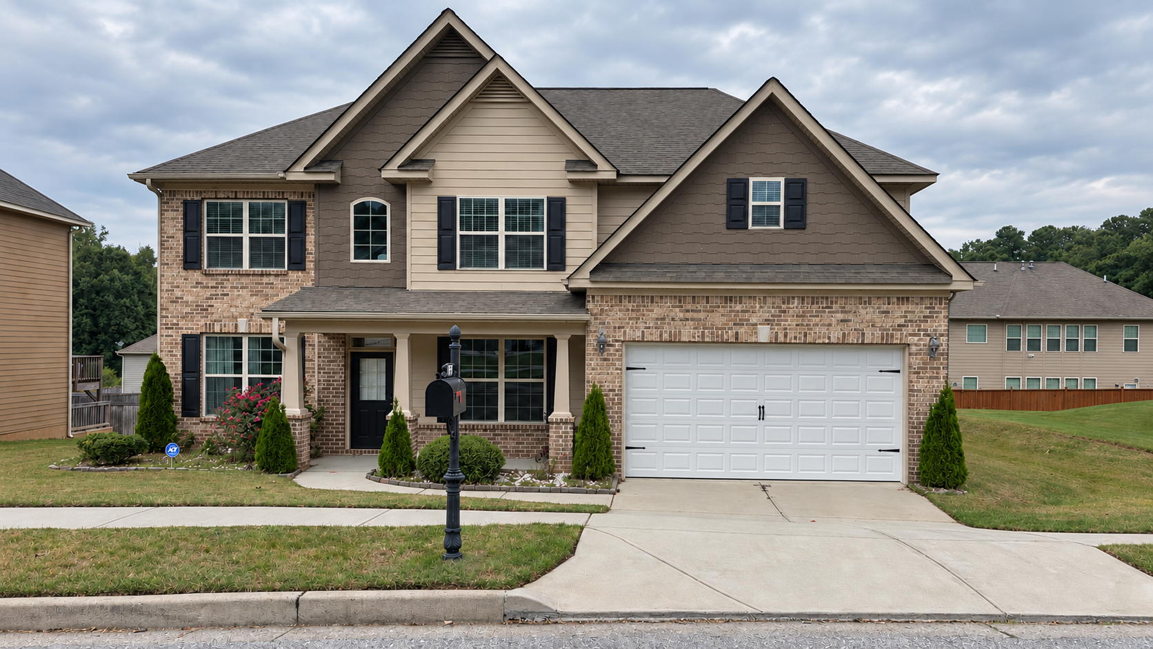 Two-story beige brick house with a white garage and a driveway on a suburban street