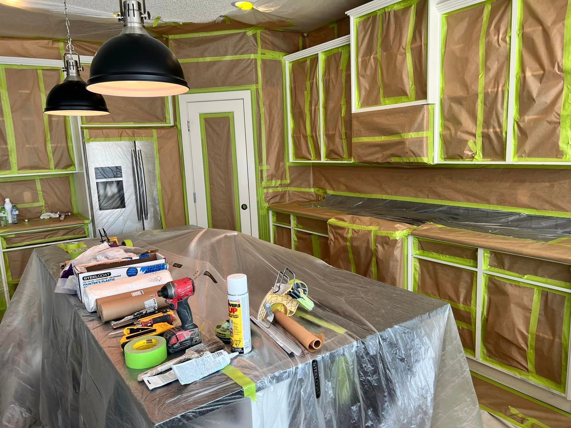 A kitchen is being painted and has a table with tools on it.