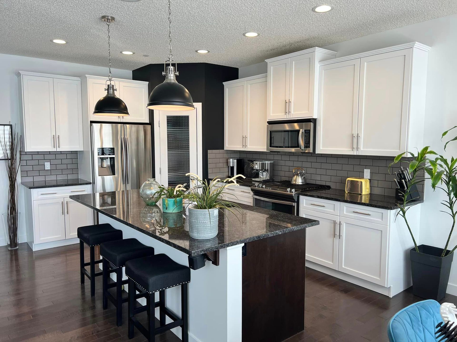 A kitchen with white cabinets , granite counter tops , stainless steel appliances and a large island.
