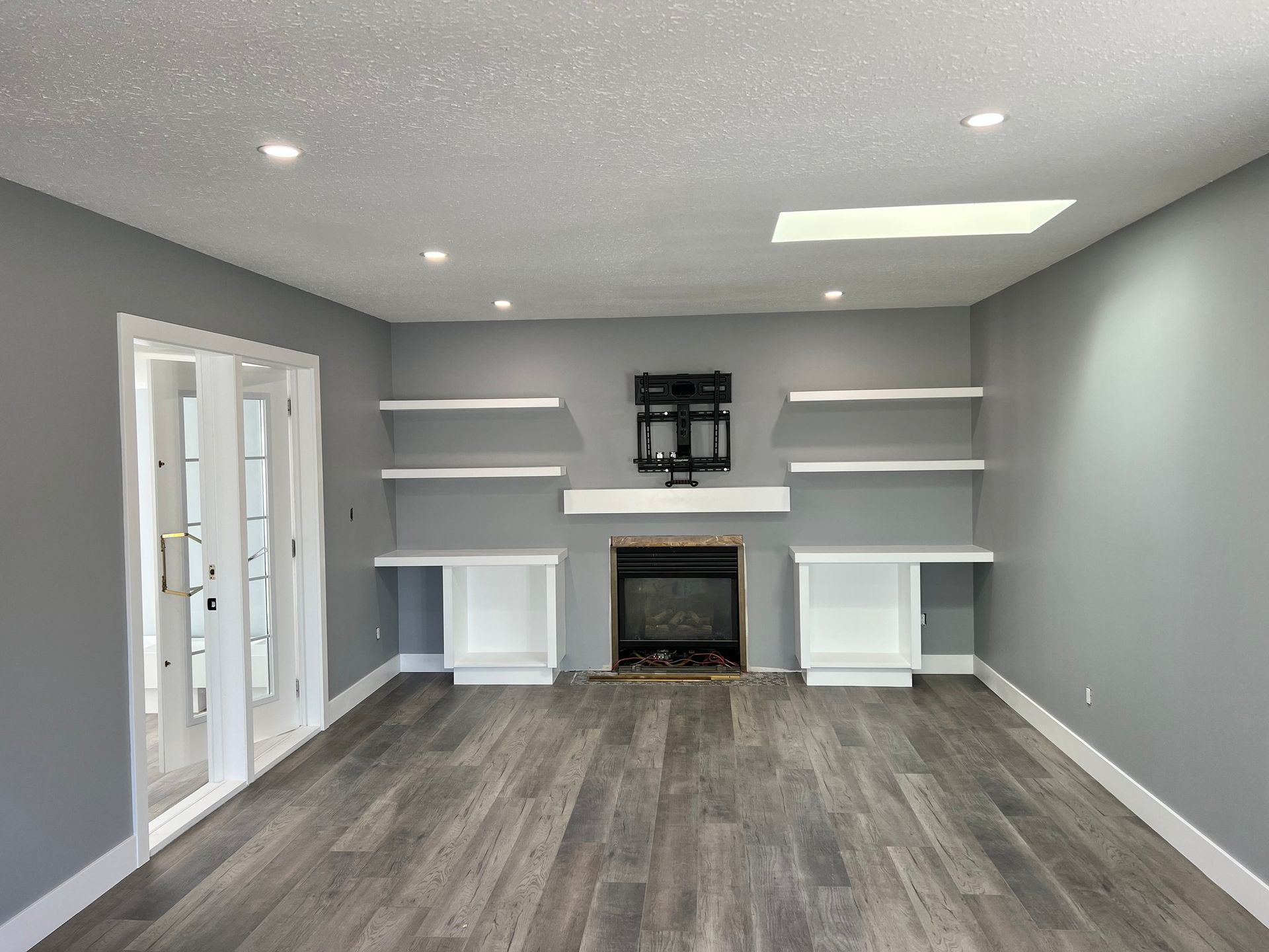 An empty living room with a fireplace and shelves