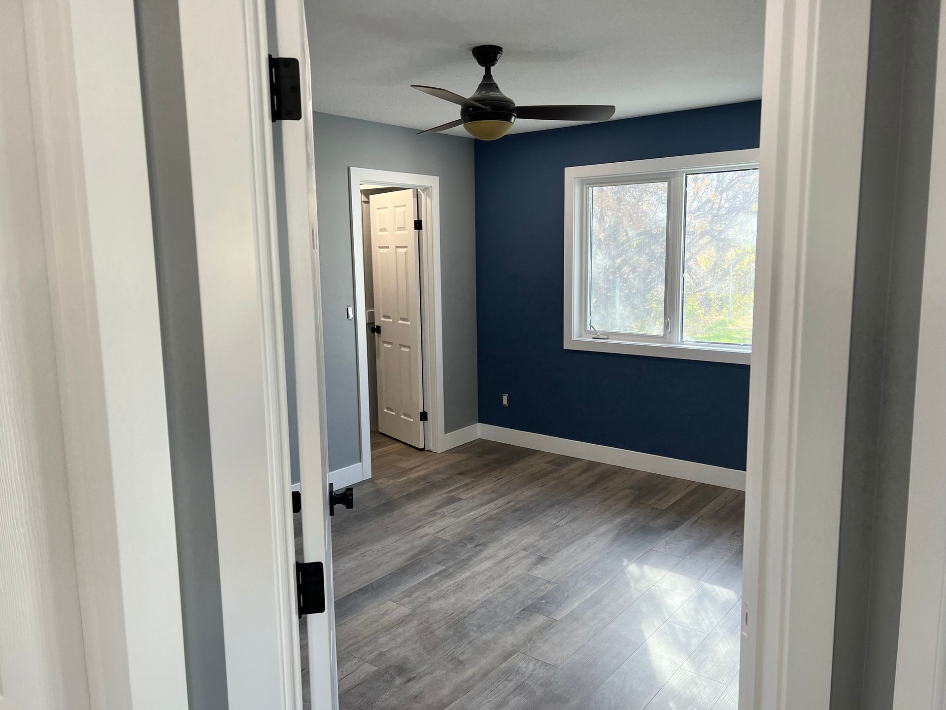 A bedroom with blue walls and a ceiling fan.