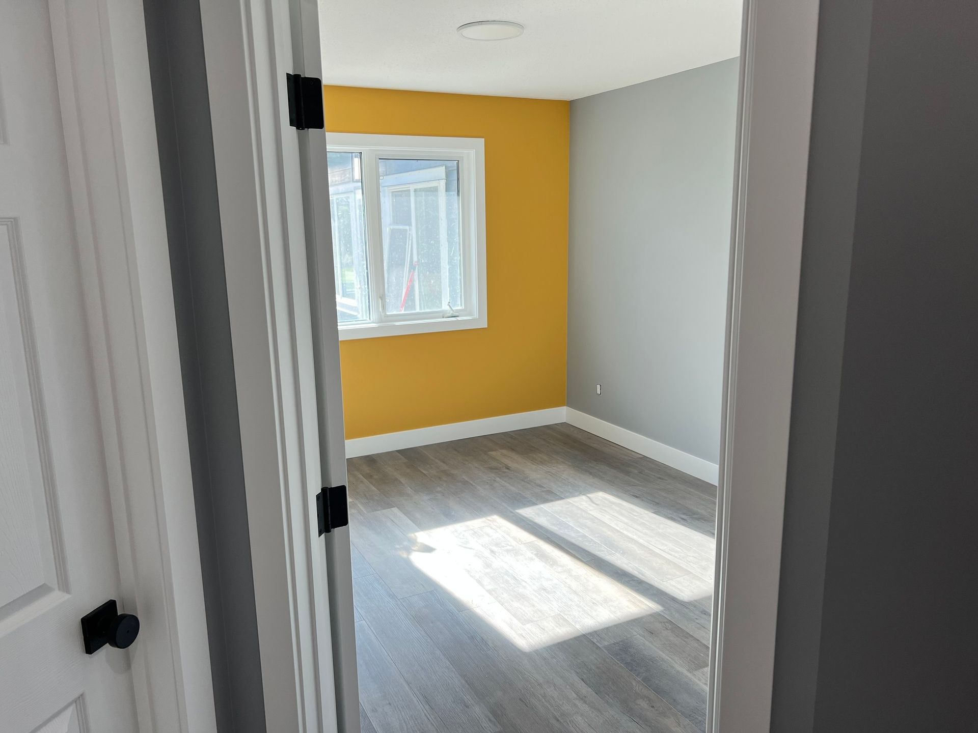 An empty room with yellow walls and a window.