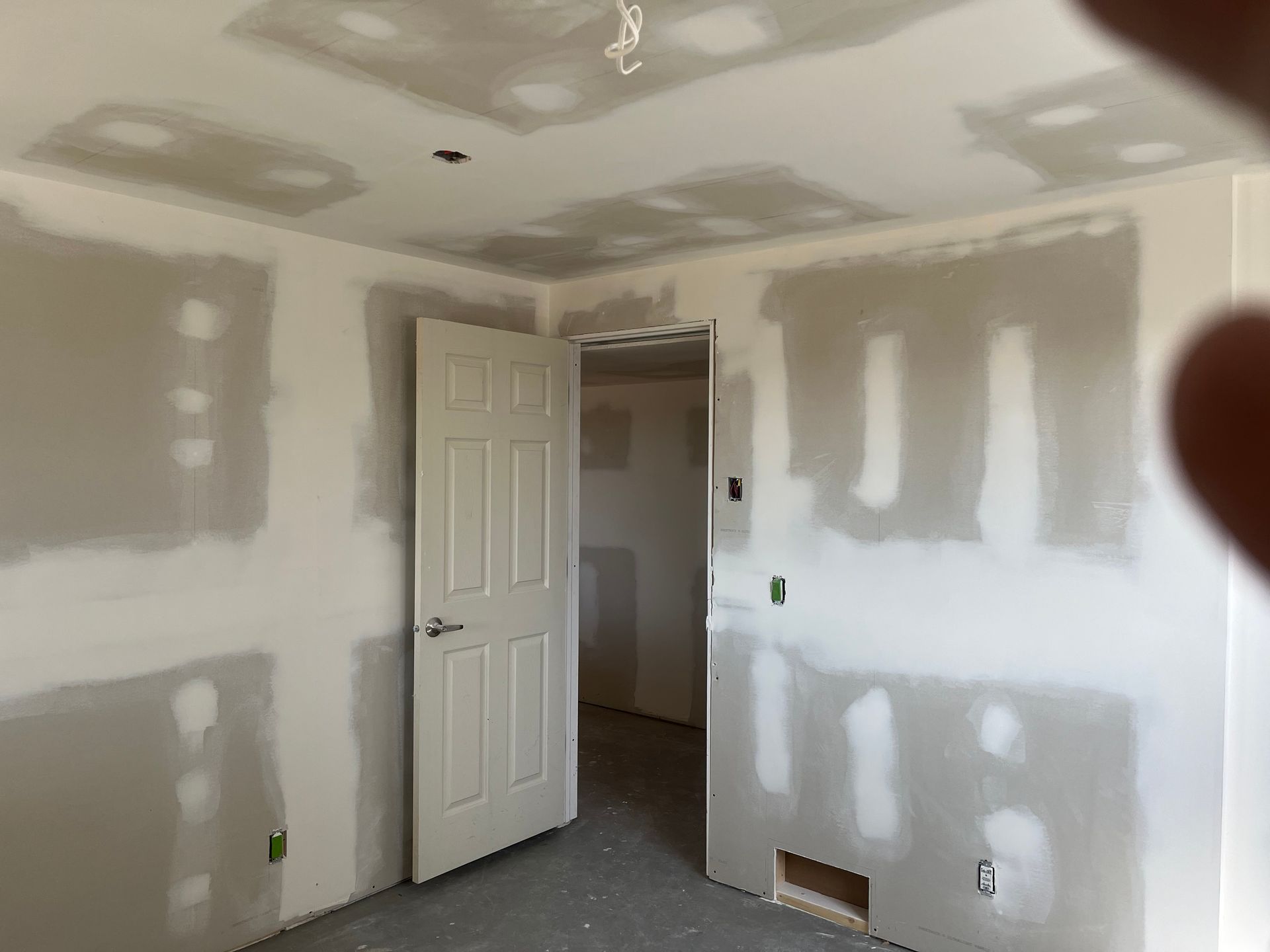 A room with drywall on the walls and a door.