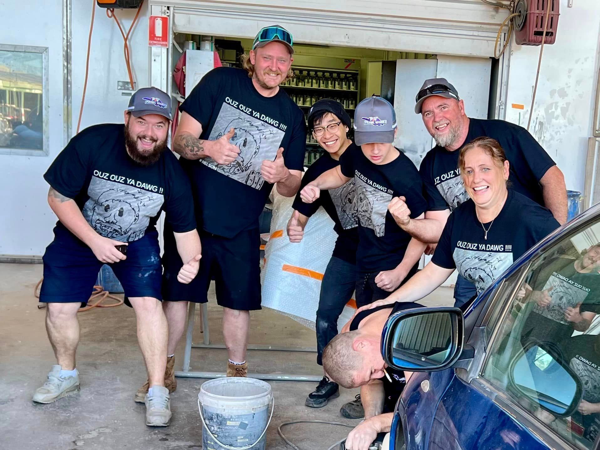 A Group Of People Are Posing For A Picture In Front Of A Car — P & V Panel Works In Alice Springs, NT