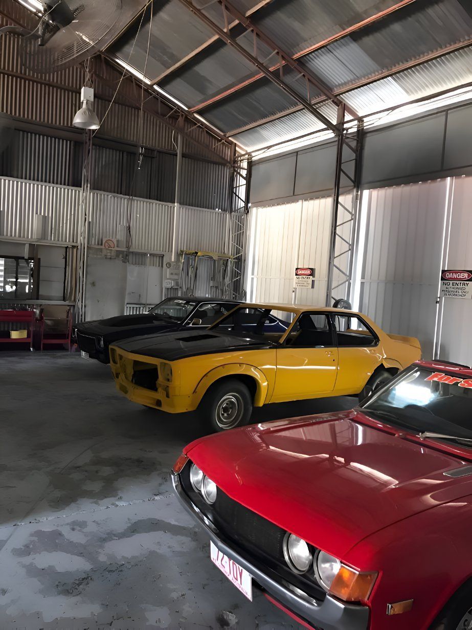 A Row Of Cars Are Parked In A Garage — P & V Panel Works In Alice Springs, NT