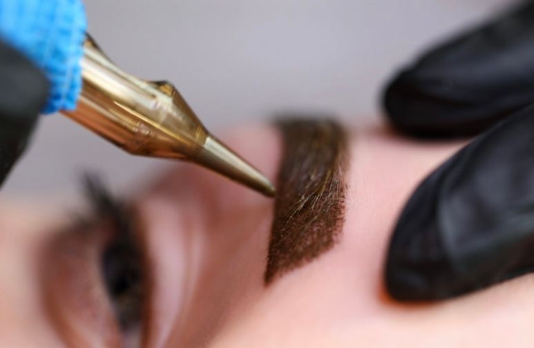A close up of a person getting a tattoo on their eyebrows.