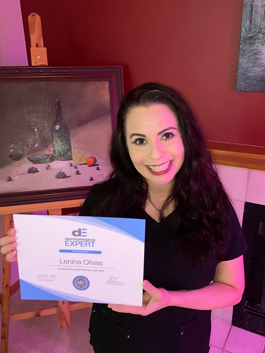 A woman is holding a certificate in front of a painting.