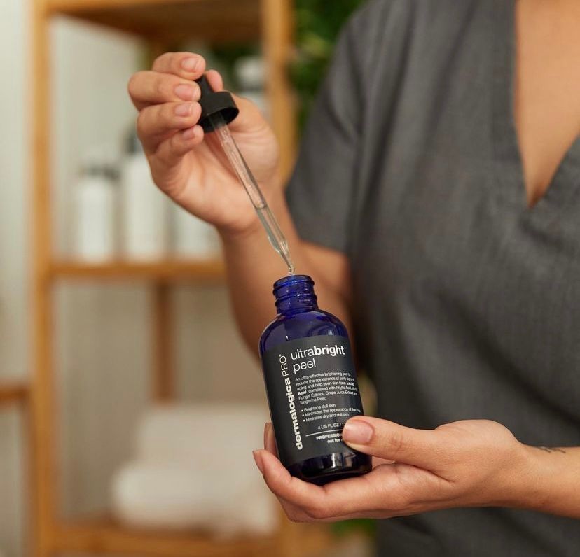 A woman is holding a blue bottle with a dropper in her hand.