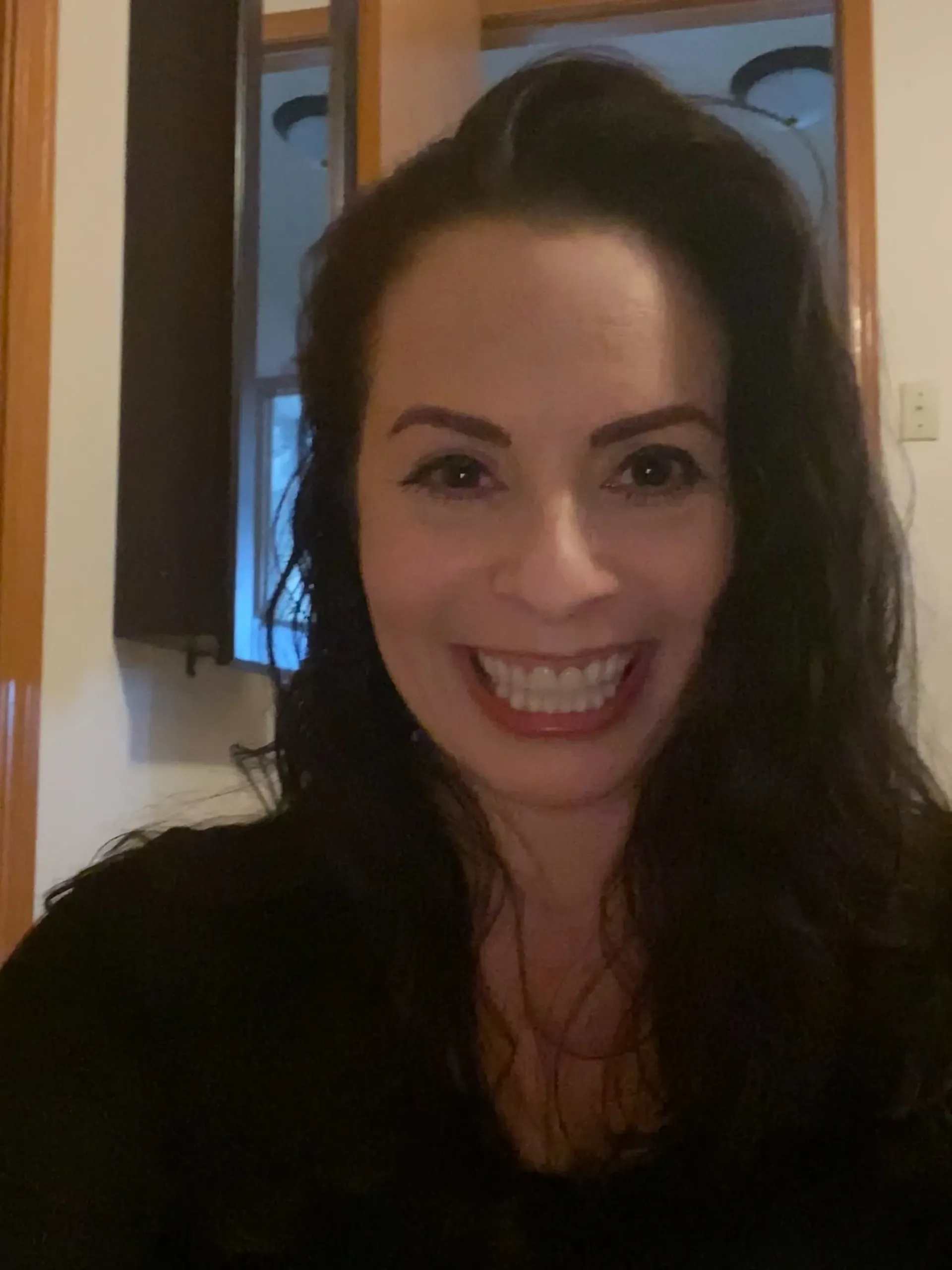 A woman with long dark hair is smiling for the camera.