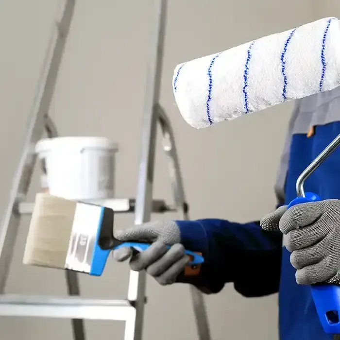 painter holding brush and roller near ladder