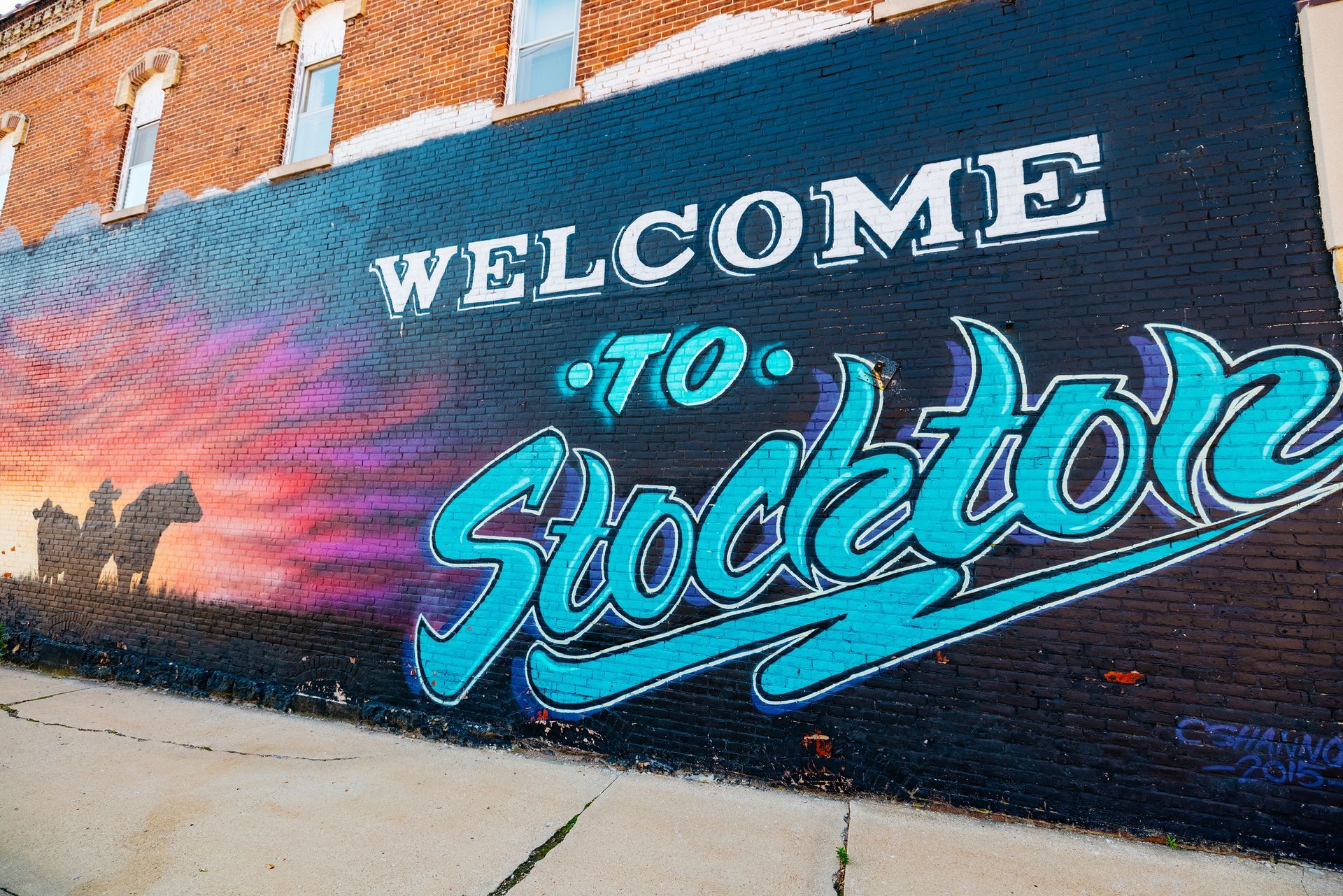 Colorful mural reading “Welcome to Stockton” on a brick building