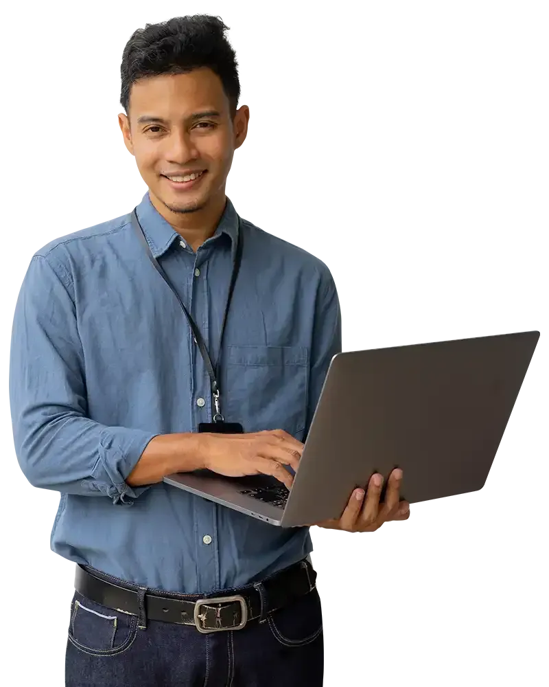 Person in a blue shirt holding a laptop and smiling at the camera.