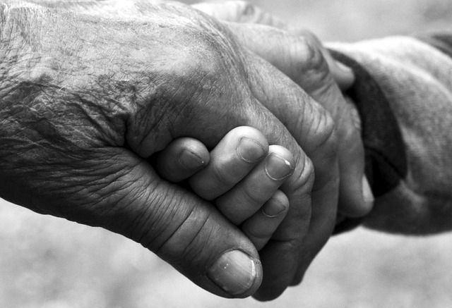 A man and a woman are holding hands over a wooden table.