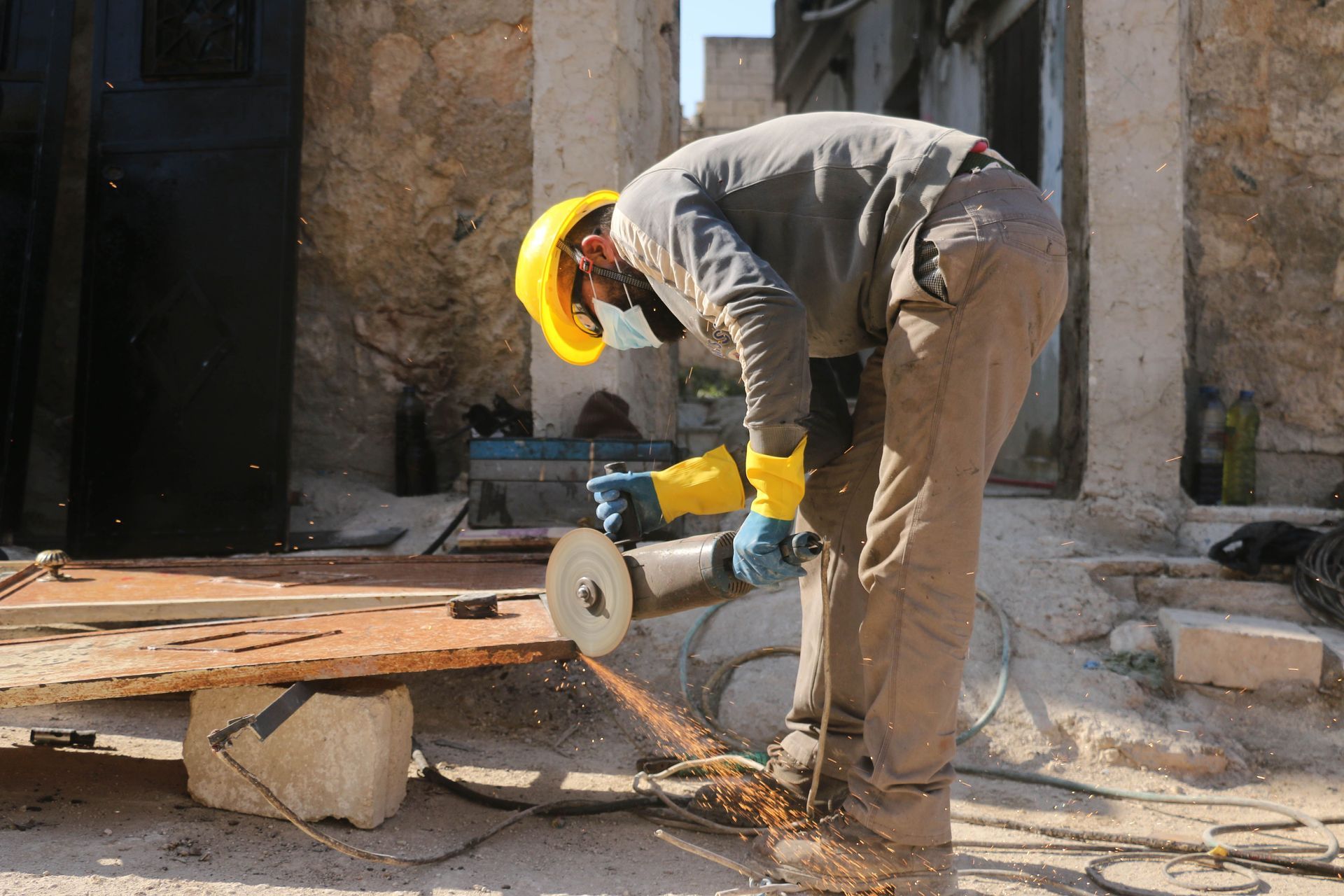 Un ouvrier portant un casque de chantier jaune coupe du bois avec une scie circulaire sur un chantier de construction.