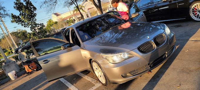 A silver car is parked in a parking lot next to a black car.