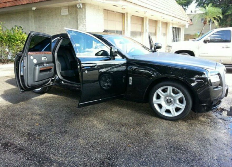 A black car with its doors open is parked in front of a building