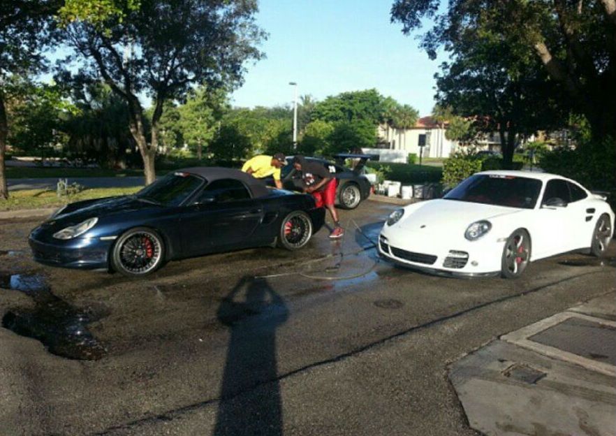 Two sports cars are being washed in a parking lot