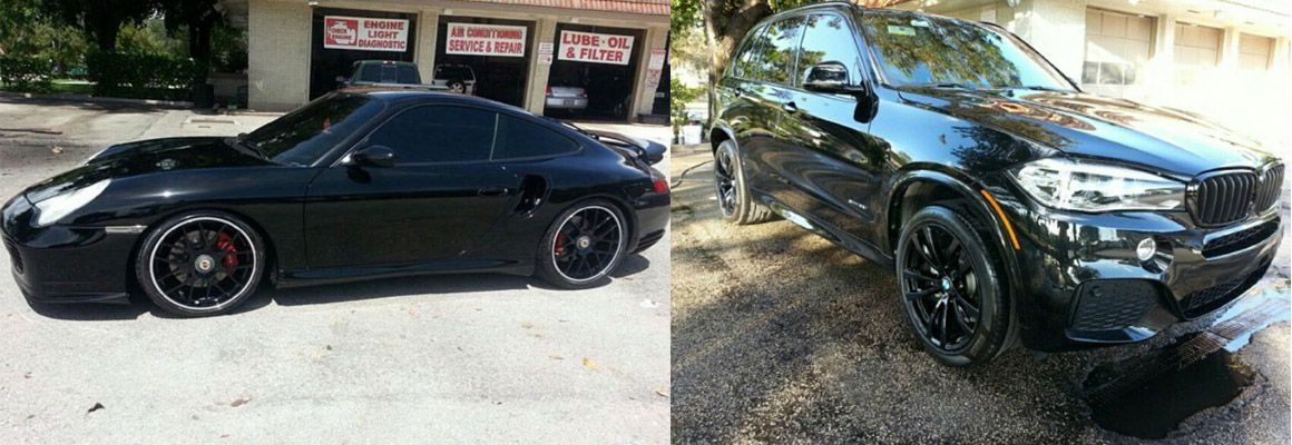 A black car is parked next to a black suv.