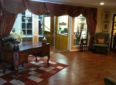 Elegant office lobby with a wooden desk, red rug, and large windows with draped curtains