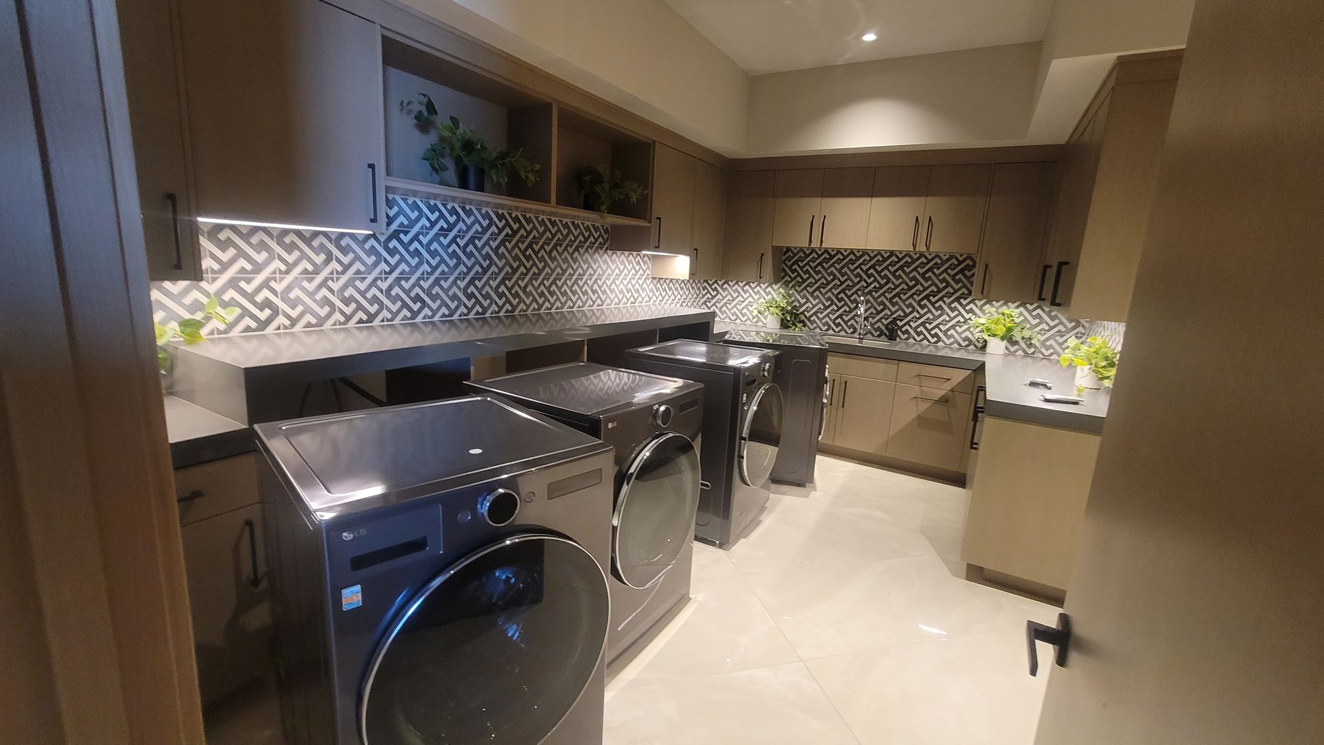 Modern kitchen with stainless steel appliances, glossy cabinets, and patterned backsplash under warm lighting