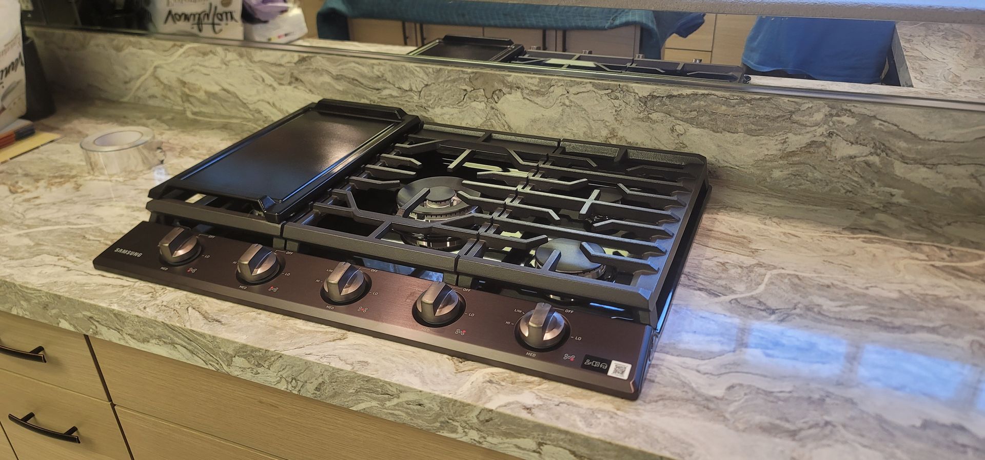 Outdoor stone countertop with a stainless steel gas cooktop and black grill cover-cover ליד?