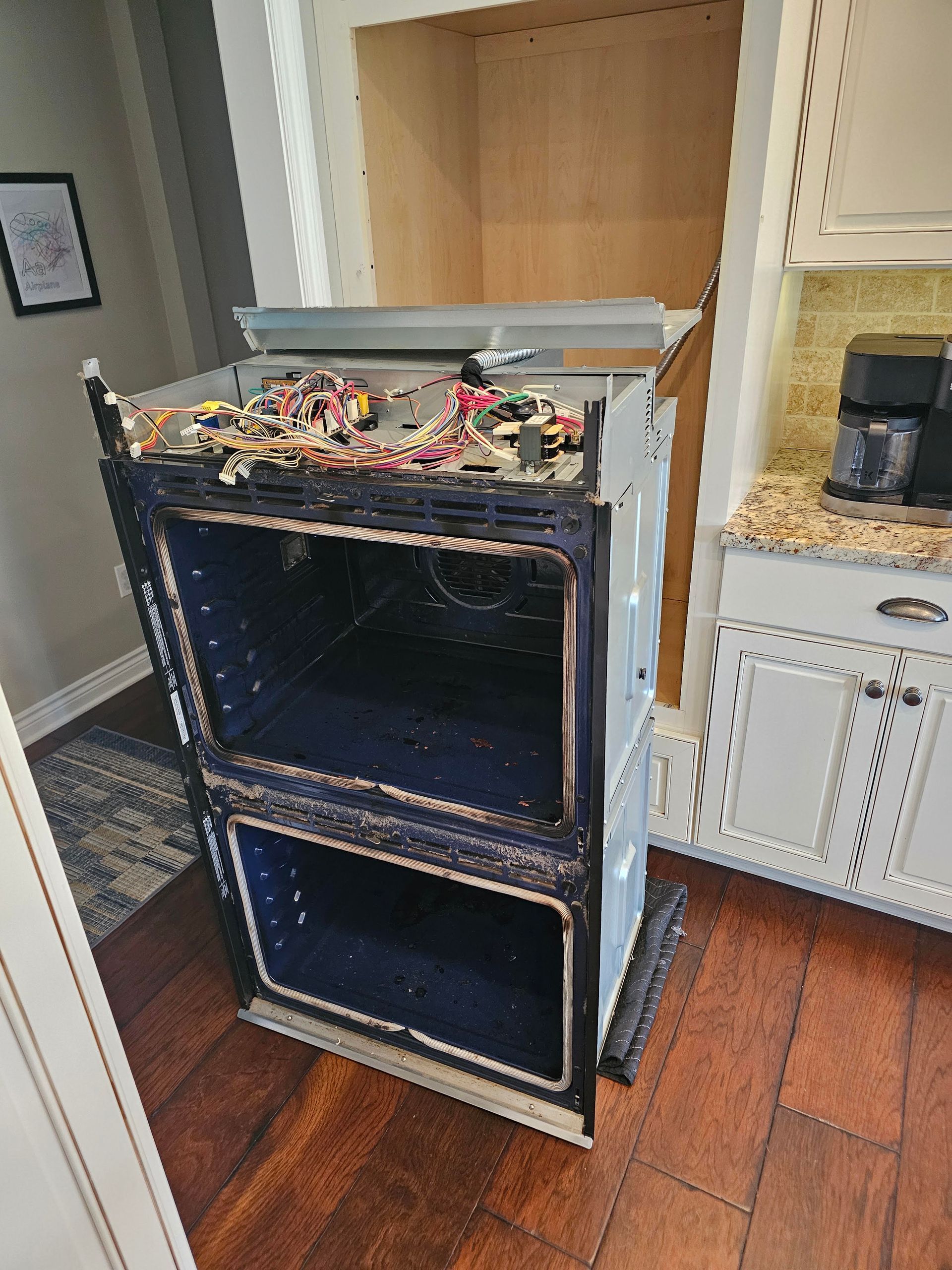 Black stove or oven in a kitchen, with debris piled on top and open front doors.