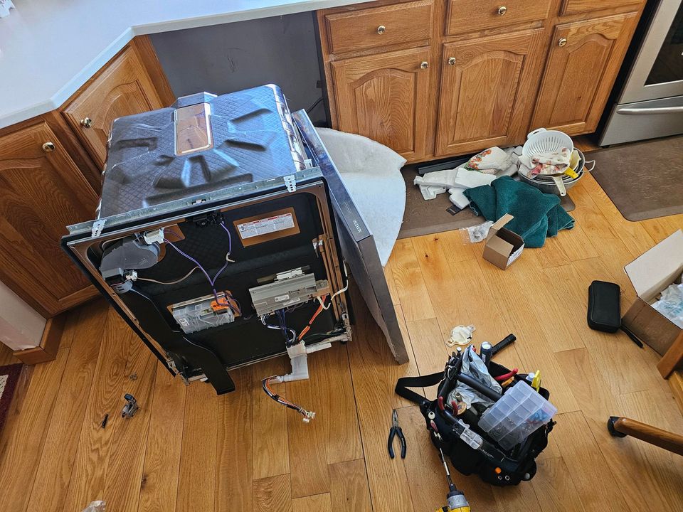 Damaged speaker cabinet on wooden floor with scattered items and tools in a kitchen-like room
